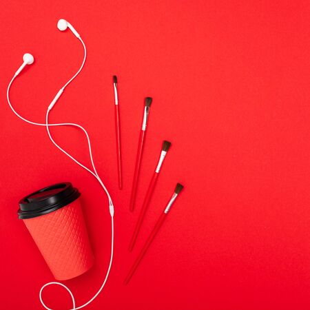 minimalism concept. paint brushes and coffee mug on a red background with copy space.の写真素材