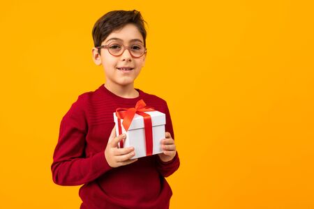 caucasian boy with gift box on yellow background with copy space.の写真素材