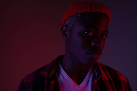 Closeup portrait of a charming handsome black man looking at the camera in neon light in the shade.の写真素材