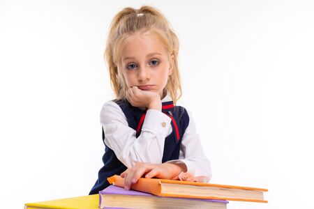 Young schoolgirl with blonde hair holds a lot of books isolated on white background.の写真素材