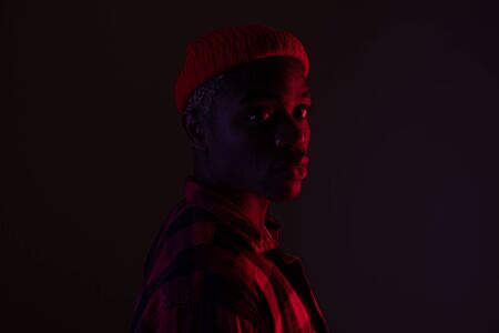 Closeup portrait of a stylish handsome black man looking at the camera in neon light in the shade.の写真素材