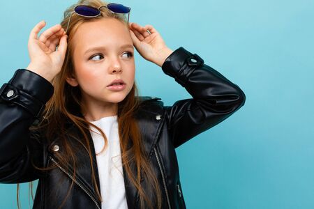 Pretty caucasian teenager girl with long brown hair in black jacket and denim jeans holds black...
