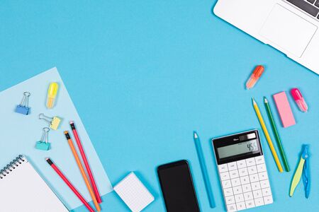 Calculator, laptop, mobile phone, notes, pens, pencils, ruler, eraser, compass isolated on blue and...