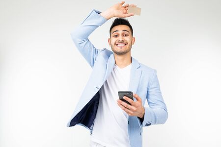 handsome man in a jacket orders purchases via the Internet from a smartphone holding a credit card...