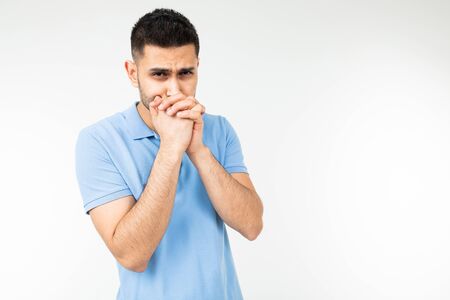 Caucasian man in a blue T-shirt sincerely asks for something on a white isolated background.の写真素材
