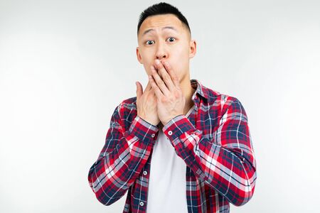A handsome asian guy in a checkered shirt wide open sends an air kiss on a white