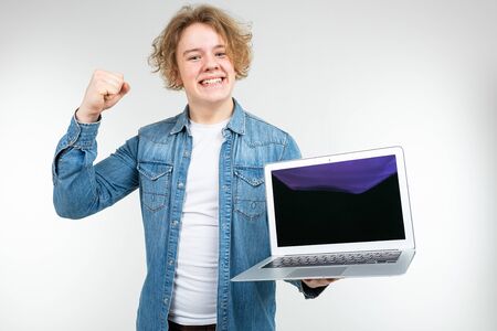 contented cool blond man holding a laptop with a layout for inserting a page on a white background.の写真素材