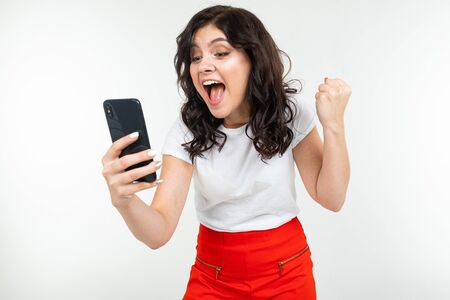 happy girl dancing with joy realizing about winning in a draw on the Internet holding a phone in her...