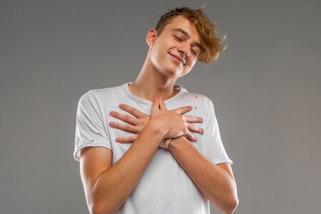cool guy in a white shirt shows dislike on a gray background.の写真素材