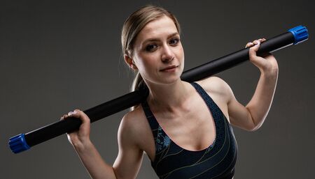 Portrait of beautiful caucasian female with long fair hair in sport wear do exercises with sport...