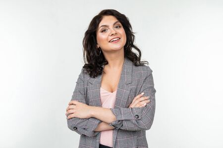 pretty woman with black hair in a checkered gray jacket for office on a white background with copy space.の写真素材