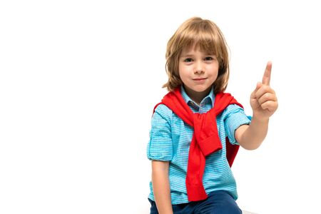 Sports teenager boy in blue t-shirt with red hoody around his neck gesticulates isolated on blue backgroundの写真素材