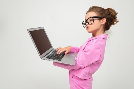 serious attractive girl with glasses in a pink suit with a laptop with a mockup on a white studio background.の写真素材