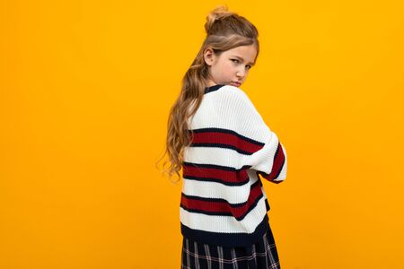 offended sad teenager girl in a striped sweater with arms crossed on an orange background with copy space.の写真素材