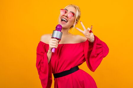 European sexy girl leading the event in a red dress with bare shoulders with a microphone in her handsの写真素材
