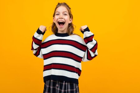 attractive girl with wide open mouth shouting news on a yellow studio background with copy space.