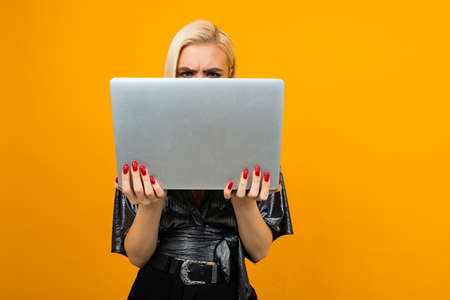 joyful girl ordered educational courses on the Internet with a laptop in her hands on a yellow studio backgroundの写真素材