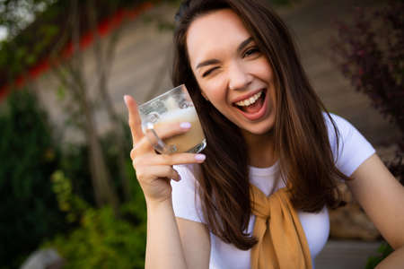 cute free young woman enjoy coffee while sitting in a beautiful summer park on the stone.の写真素材