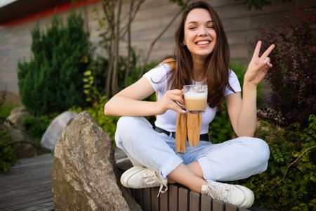 charming free young woman in casual look drinking coffee in the street.の写真素材