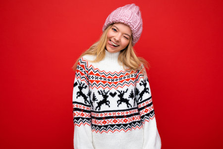 Photo of pretty positive smiling young blonde woman isolated over red background wall wearing winter...