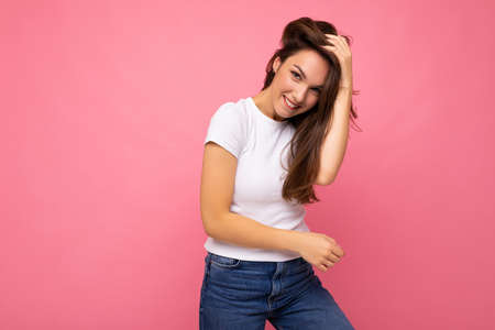 Portrait of positive cheerful fashionable woman in casual white t-shirt for mock up isolated on pink...