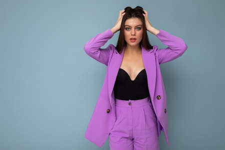 Photo of positive young business long hair brunette woman wearing purple suit isolated on blue background. Copy space.の写真素材