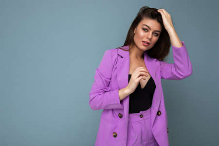 Photo of positive young business long hair brunette woman wearing purple suit isolated on blue background. Copy space.の写真素材