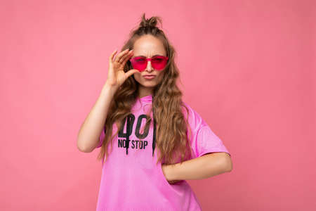 Photo shot of pretty sad dissatisfied young blonde curly woman isolated over pink background wall...