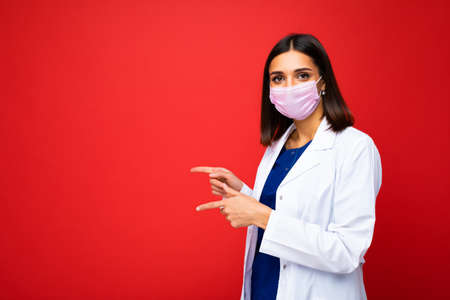 Woman in virus protective mask on face against  and white medical coat isolated on the background...