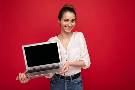 portrait of Beautiful smiling happy young woman holding computer laptop looking at camera having fun...