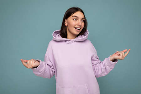 Shot of attractive happy smiling young woman wearing casual outfit standing isolated over colourful background with empty space looking to the sideの写真素材