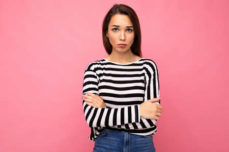 Photo shot of cute attractive pretty young sad upset brunette woman wearing casual striped longsleeve isolated over colorful background with copy spaceの写真素材