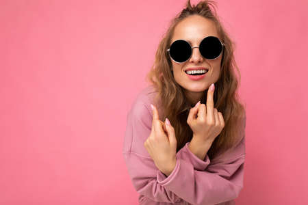 Photo of young positive happy smiling beautiful woman with sincere emotions wearing stylish clothes isolated over background with copy space and showing fuckの写真素材