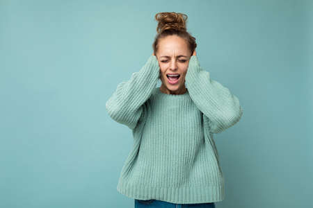 Portrait of young emotional attractive blonde woman with sincere emotions wearing casual blue jersey...