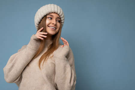 Beautiful positive happy young dark blonde woman isolated over colourful background wall wearing casual stylish clothes feeling sincere emotions looking to the sideの写真素材