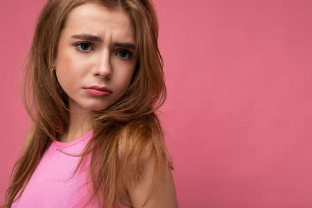 Closeup photo of dissatisfied sad young beautiful dark blonde female person with sincere emotions isolated on background wall with copy space wearing stylish pink top. Negative conceptの写真素材