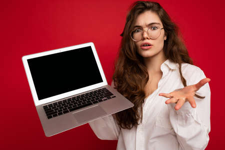 Shocked amazed withless beautiful brunette curly young woman sayong wow holding computer laptop...