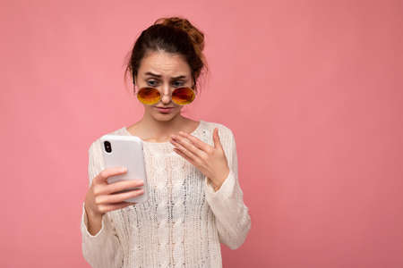 Photo of attractive dissatisfied young woman wearing casual white blouse and colorful sunglasses...