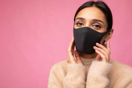 Women wearing a stylish protective face mask, posing on pink background.の写真素材