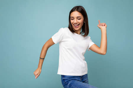 Photo of positive smiling young beautiful brunette woman with sincere emotions wearing casual white...