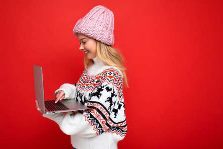 side profile photo of charming pretty young lady holding laptop isolated over wall background typing on keyboardの写真素材