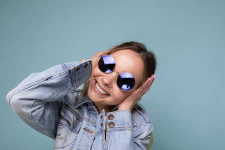 closeup shot of pretty positive smiling young blonde woman wearing blue jean jacket and stylish...
