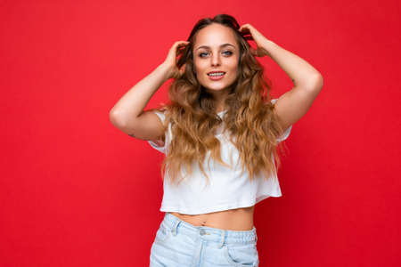 Young beautiful blond woman wearing white t-shirt looking at camera. Positive female shows facial...