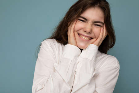 Portrait of beautiful positive cheerful cute smiling young brunette woman in casual white shirt...
