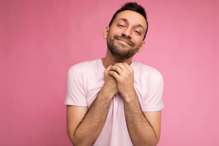 Photo of handsome happy cute positive brunet man in casual pink t-shirt isolated on pink background with copy space for textの写真素材