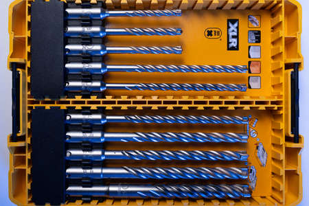 Closeup photo shot of yellow and transparent kit box with drills for drilling holes on a white table . Repair and construction conceptのeditorial素材