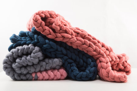 a stack of knitted blankets from natural materials on a white background concept of warmth and comfort from sheep woolの写真素材