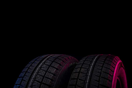 two black tires with winter tread on a black background