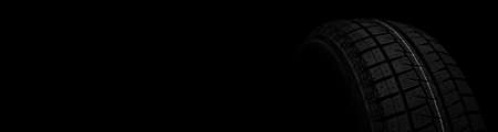 black tire with winter tread on a black stylish background close-up