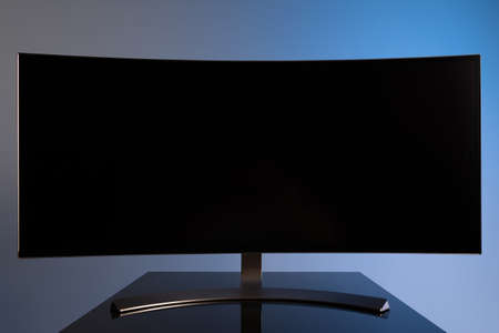 professional widescreen curved gaming monitor close-up on gray-blue stylish backgroundの写真素材